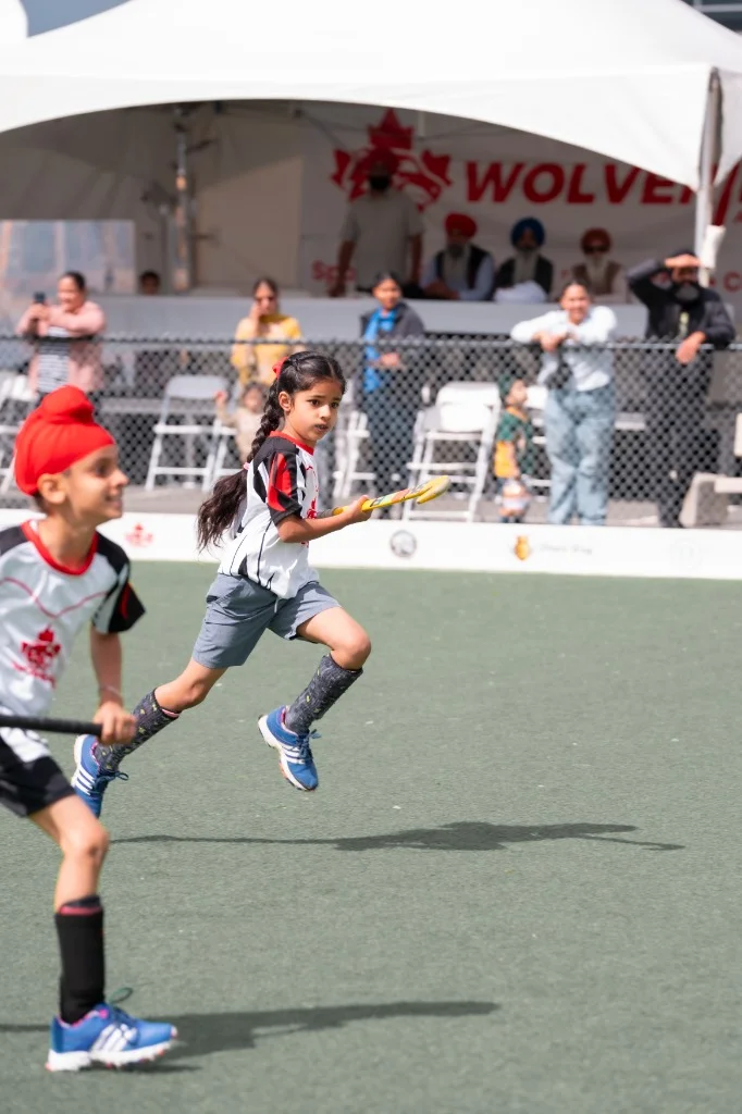 Junior player sprinting with stick down field during tournament match